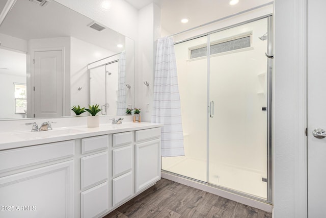 full bathroom with visible vents, a sink, a stall shower, and wood finished floors
