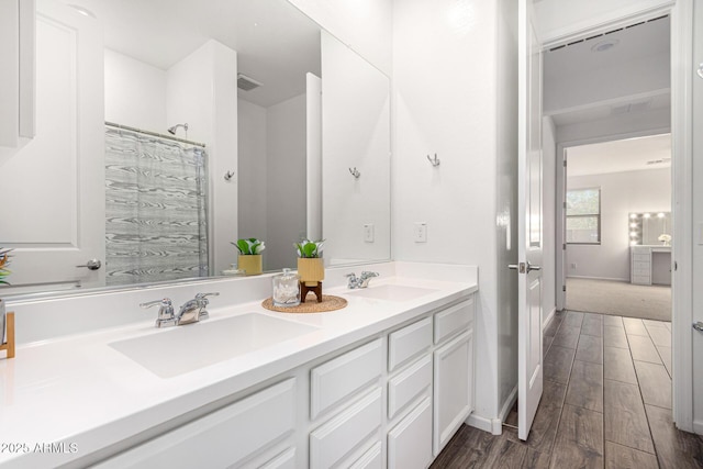 bathroom with a sink, double vanity, wood finished floors, and visible vents