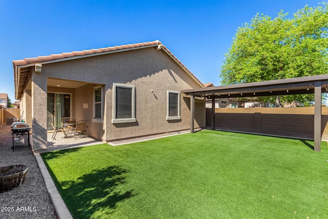 rear view of property featuring a fenced backyard, stucco siding, a yard, and a patio area