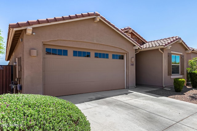 single story home featuring a garage, stucco siding, driveway, and a tile roof