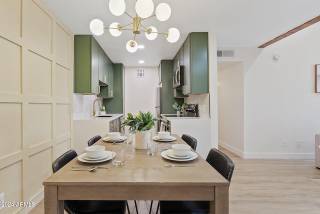 dining room with sink, light hardwood / wood-style flooring, and an inviting chandelier