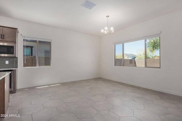 empty room featuring light tile patterned flooring and a notable chandelier