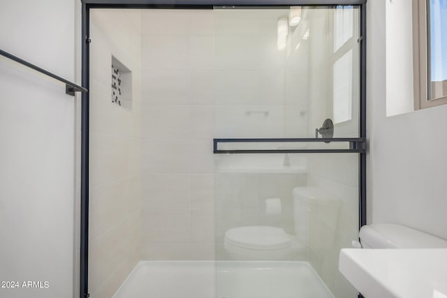 bathroom featuring a shower with door and toilet