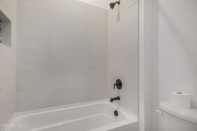 bathroom with toilet and tiled shower / bath combo