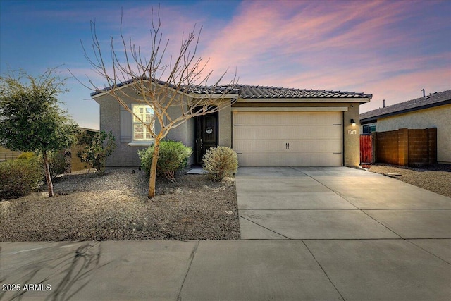 single story home with stucco siding, driveway, a tile roof, fence, and a garage