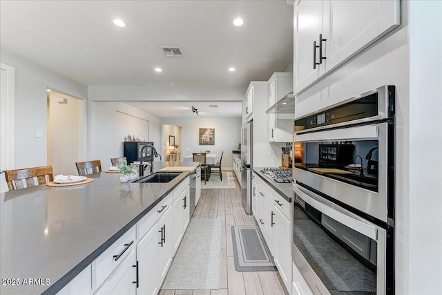 kitchen with visible vents, appliances with stainless steel finishes, wood tiled floor, and a sink