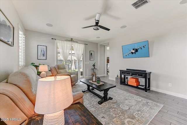 living room featuring visible vents, ceiling fan, baseboards, and wood finished floors