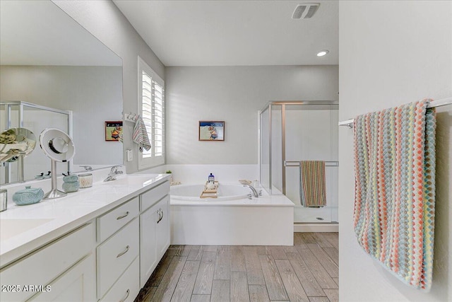 bathroom featuring visible vents, a stall shower, a sink, and wood finished floors