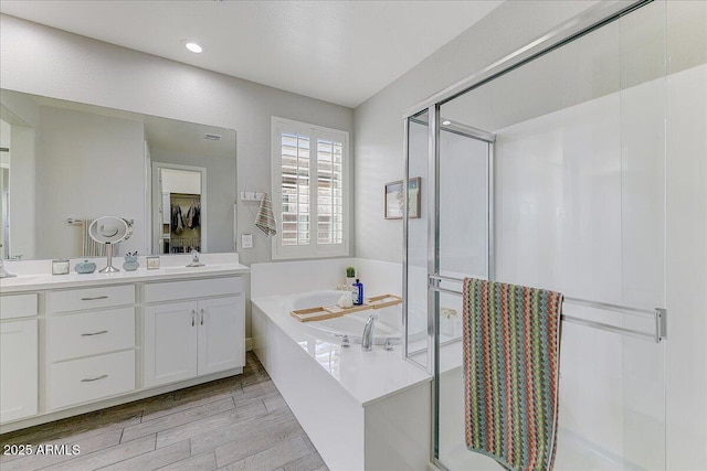bathroom with vanity, a bath, wood finished floors, and a stall shower