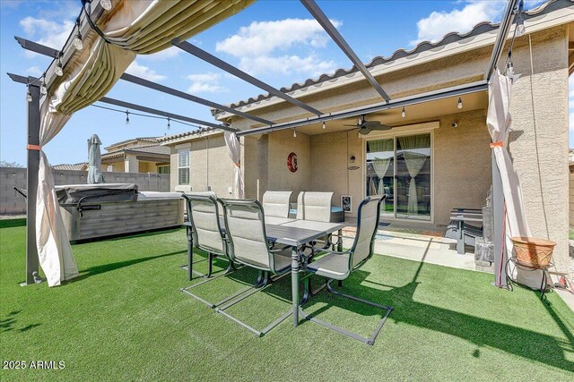 exterior space featuring a hot tub, ceiling fan, fence, glass enclosure, and outdoor dining space