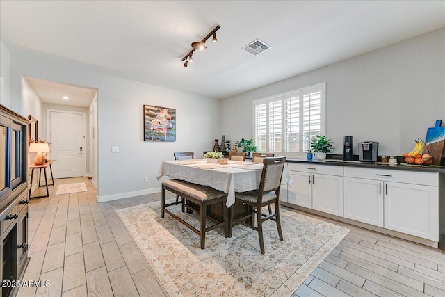 dining area featuring light wood-type flooring, baseboards, visible vents, and rail lighting