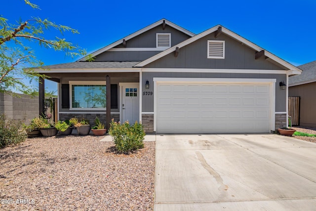 5709 S 13th Ave, Phoenix, AZ 85041 - view of front of home featuring stone siding, concrete driveway, a garage, and a shingled roof