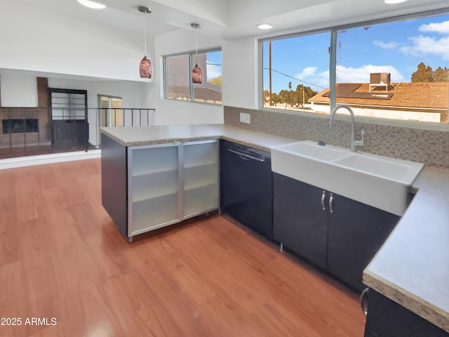 kitchen featuring dishwasher, sink, hanging light fixtures, light wood-type flooring, and kitchen peninsula