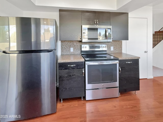 kitchen featuring appliances with stainless steel finishes, light wood-type flooring, and tasteful backsplash