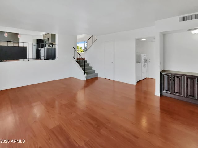 unfurnished living room with wood-type flooring and washing machine and dryer