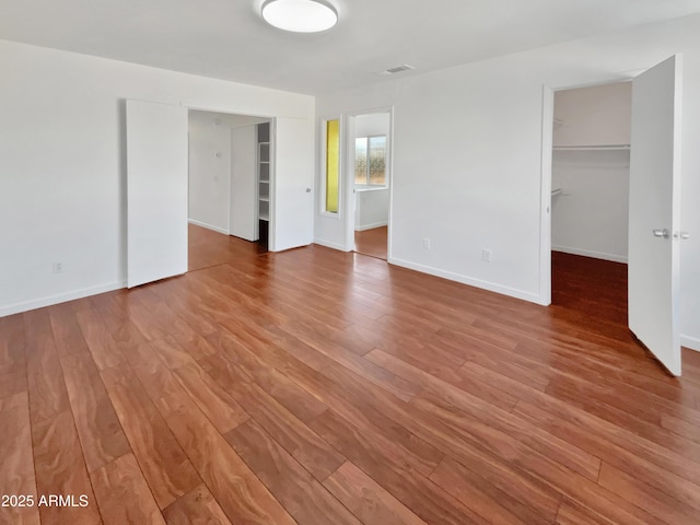 unfurnished bedroom featuring hardwood / wood-style flooring, a spacious closet, and a closet