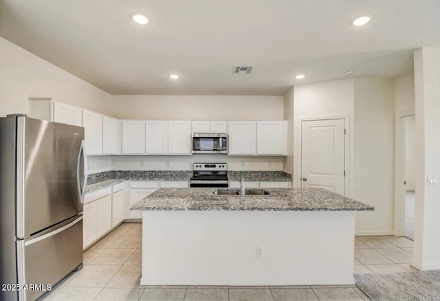 kitchen featuring light stone counters, a center island with sink, stainless steel appliances, and a sink