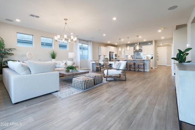 living room with an inviting chandelier and light wood-type flooring