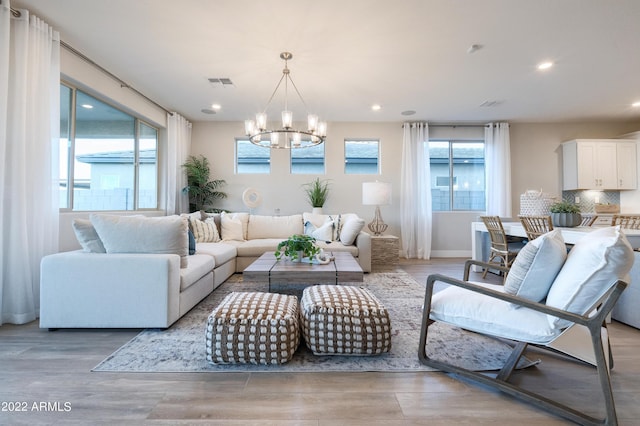 living room with a notable chandelier, plenty of natural light, and light wood-type flooring