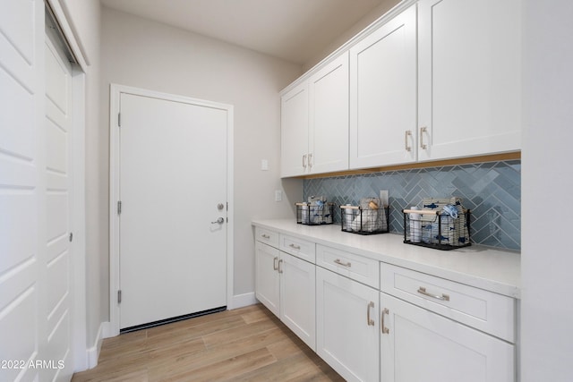 bar featuring backsplash, white cabinets, and light wood-type flooring