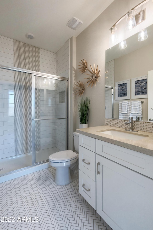 bathroom with vanity, toilet, a shower with shower door, and tile patterned flooring