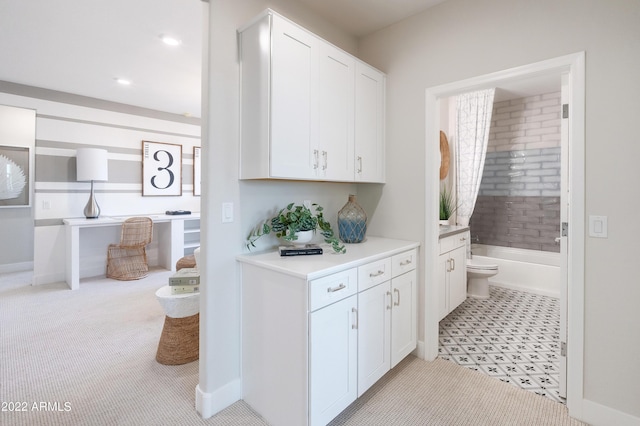 kitchen with light carpet and white cabinets