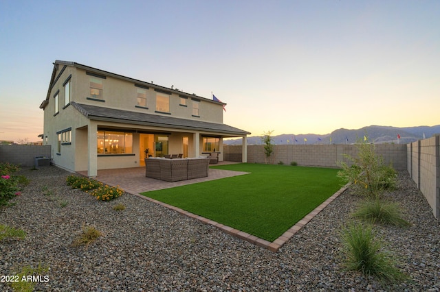 back house at dusk with a patio area, central air condition unit, a lawn, outdoor lounge area, and a mountain view