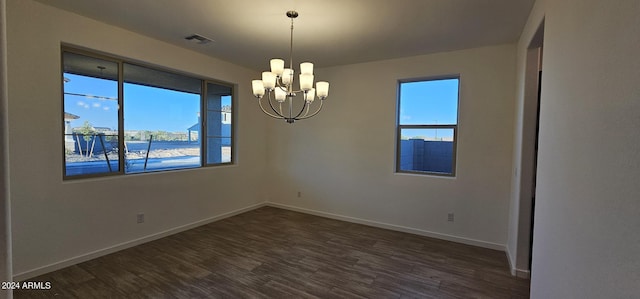 spare room with an inviting chandelier and dark hardwood / wood-style floors