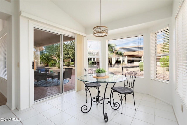 tiled dining room with lofted ceiling and a notable chandelier