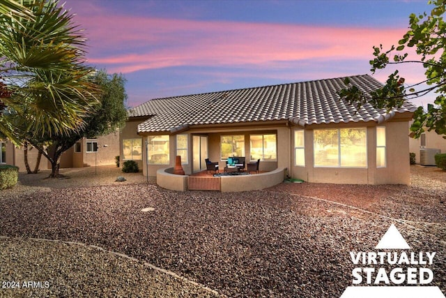 back house at dusk featuring central air condition unit and a patio area