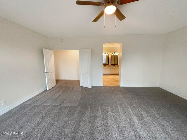 unfurnished bedroom with ceiling fan, carpet flooring, and ensuite bath