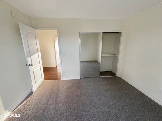 unfurnished bedroom with a closet and dark colored carpet