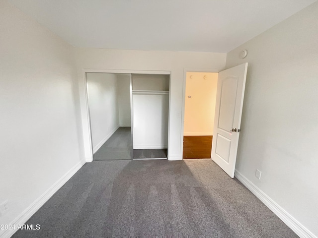 unfurnished bedroom with a closet and dark colored carpet