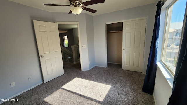 unfurnished bedroom featuring dark colored carpet, ceiling fan, and a closet