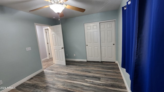 unfurnished bedroom with dark wood-type flooring, a closet, and ceiling fan