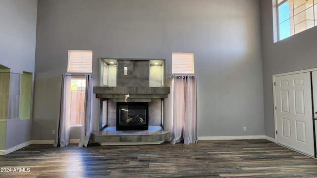 unfurnished living room with plenty of natural light, dark hardwood / wood-style floors, and a towering ceiling