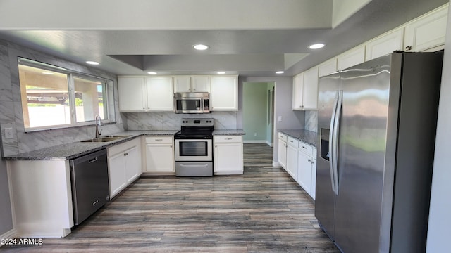 kitchen featuring sink, appliances with stainless steel finishes, dark stone countertops, white cabinets, and dark hardwood / wood-style flooring