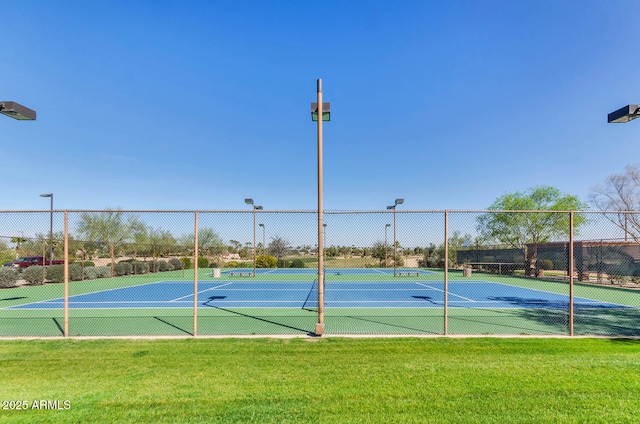 view of tennis court featuring fence and a lawn