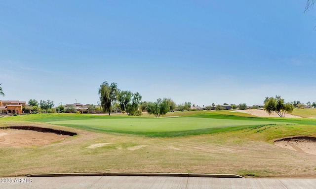 view of property's community with view of golf course and a lawn