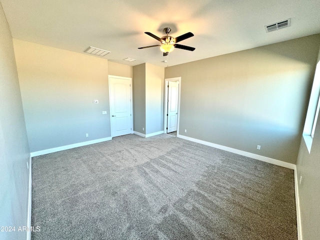 unfurnished bedroom with ceiling fan and dark carpet