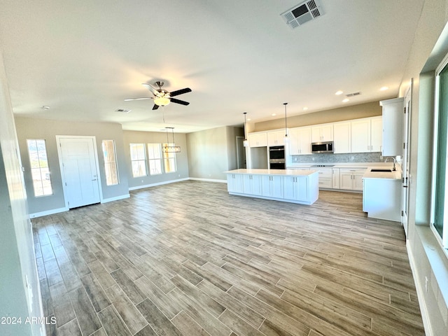 kitchen with white cabinets, light wood-type flooring, stainless steel appliances, and a kitchen island