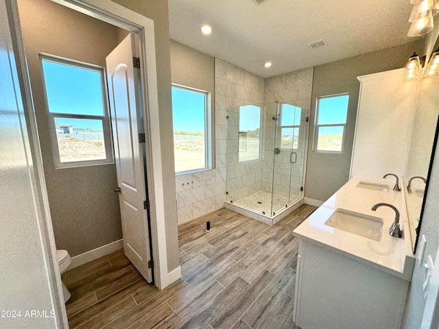 bathroom with plenty of natural light, wood-type flooring, a shower with shower door, and toilet