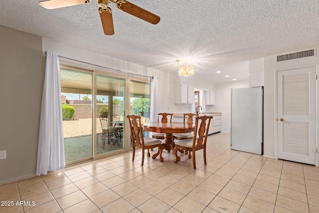 dining area with ceiling fan with notable chandelier, a textured ceiling, light tile patterned floors, and sink