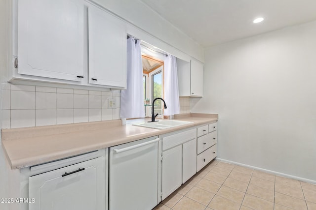 kitchen with white dishwasher, white cabinets, backsplash, and sink