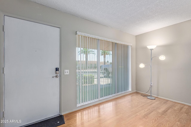 doorway to outside featuring a textured ceiling and light hardwood / wood-style floors