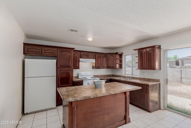 5933 W Mitchell Dr, Phoenix, AZ 85033 - kitchen with white appliances, under cabinet range hood, light tile patterned floors, open shelves, and a kitchen island