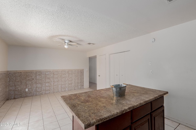 5933 W Mitchell Dr, Phoenix, AZ 85033 - kitchen featuring a ceiling fan, light tile patterned flooring, dark countertops, dark brown cabinetry, and a textured ceiling