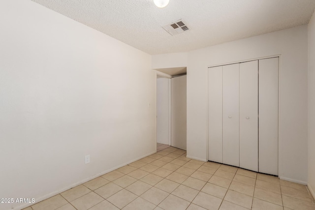 5933 W Mitchell Dr, Phoenix, AZ 85033 - unfurnished bedroom featuring a closet, a textured ceiling, and light tile patterned floors