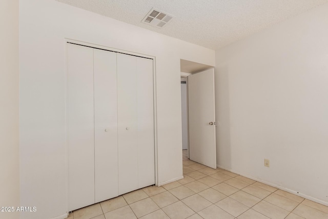 5933 W Mitchell Dr, Phoenix, AZ 85033 - unfurnished bedroom featuring a closet, a textured ceiling, and light tile patterned flooring