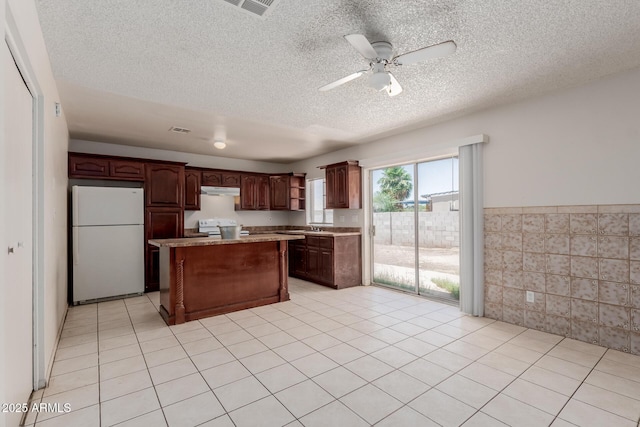 5933 W Mitchell Dr, Phoenix, AZ 85033 - kitchen featuring white appliances, a kitchen island, light countertops, a textured ceiling, and wainscoting